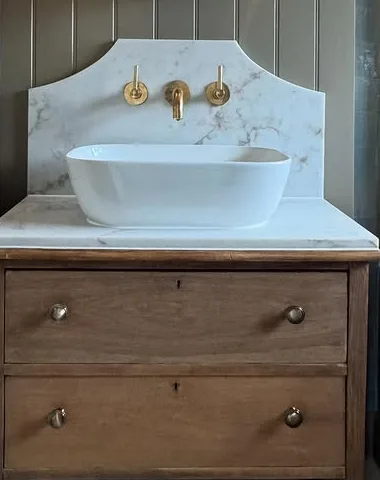 Brass wall taps over a stone basin on a marble splashback, fitted by Dan in Penwortham
